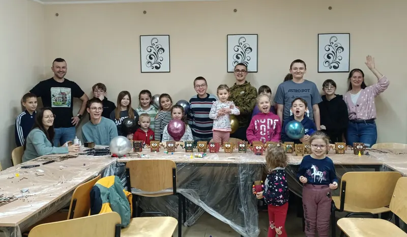 Uśmiechnięta grupa dzieci i dorosłych po warsztatach w sali